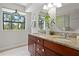 Bathroom with double sinks, granite countertops, wood cabinets, and a large window offering natural light at 308 N Shadowbay Blvd # 214, Longwood, FL 32779