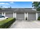 View of three garages with neutral colored doors, attached to townhome, under a bright sky at 308 N Shadowbay Blvd # 214, Longwood, FL 32779