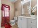 Stylish bathroom with a modern vanity, decorative mirror, window with red curtains, and elegant decor at 3640 Sail Harbor Dr, Kissimmee, FL 34746