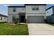 Two-story home with a well-manicured lawn, a gray two-car garage, and a cozy, covered front porch at 3823 Spruce Creek Dr, Lakeland, FL 33811