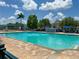 Community pool with clear turquoise water, umbrellas, lounge chairs, and a brick paver deck at 4011 Venetian Bay Village # 104, Kissimmee, FL 34741