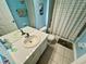 Blue-themed bathroom showcasing a double vanity, tiled floor, and shower with patterned curtain at 7682 Sir Kaufmann Ct, Kissimmee, FL 34747