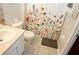 Well-lit bathroom showcasing a toilet, sink, and a decorative floral shower curtain at 7682 Sir Kaufmann Ct, Kissimmee, FL 34747