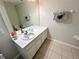 Well-lit bathroom with a large mirror, vanity, tiled floors, and neutral decor at 7682 Sir Kaufmann Ct, Kissimmee, FL 34747