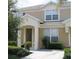 Inviting two-story townhome featuring a covered entry, tan stucco exterior, and well-maintained landscaping at 7682 Sir Kaufmann Ct, Kissimmee, FL 34747