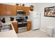 Efficient kitchen featuring stainless steel appliances, wood cabinets, and a white refrigerator at 7682 Sir Kaufmann Ct, Kissimmee, FL 34747