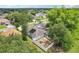 An aerial view of a blue home with solar panels and a fenced backyard situated in a green, tree-filled neighborhood at 857 Marquis Ct, Kissimmee, FL 34759