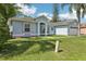 A charming blue single-story home featuring an arched entryway and two-car garage, complemented by a lush green lawn at 857 Marquis Ct, Kissimmee, FL 34759