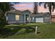 Charming single-story home with a well-manicured lawn, side garage, and tropical trees at 857 Marquis Ct, Kissimmee, FL 34759