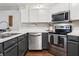 A partial view of the kitchen with stainless steel appliances and gray cabinets with white countertops at 857 Marquis Ct, Kissimmee, FL 34759