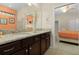 Bathroom with dual sinks, granite counters, dark wood cabinets, and view to bedroom at 8912 Rhodes St, Kissimmee, FL 34747