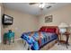 Cozy bedroom with ceiling fan, television, carpet, bed with quilt and a side table with lamp at 9324 Carolview Way, Orlando, FL 32836