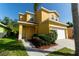 Charming yellow two-story home with a well-manicured lawn and inviting curb appeal on a sunny day at 1129 Royal Ridge Dr, Davenport, FL 33896
