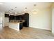 A spacious kitchen featuring black cabinets, granite countertops, a large island, and wood-look tile flooring at 1222 Castlevecchio Loop, Orlando, FL 32825