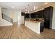 An open-concept kitchen featuring a large island with dark cabinets, a staircase, and wood-look tile at 1222 Castlevecchio Loop, Orlando, FL 32825