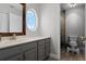 Modern bathroom with vanity, decorative mirror, and large, unique oval window for natural light at 13431 Early Frost Cir, Orlando, FL 32828