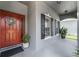 Inviting front porch featuring a red door with wreath, black shutters, and potted plants at 13431 Early Frost Cir, Orlando, FL 32828