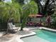 Outdoor pool area with a egg chair, lounge seating, a red umbrella, and lush palm trees at 1420 Knollwood St, Orlando, FL 32804