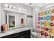 Bathroom with a colorful shower curtain, granite vanity, and a large mirror with decorative lighting at 15577 Willow Arbor Cir, Orlando, FL 32824