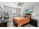 Comfortable bedroom with orange quilt, a fan, artwork, and a window, creating a relaxing atmosphere at 15577 Willow Arbor Cir, Orlando, FL 32824