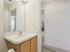 Compact bathroom featuring a sink vanity with storage, mirror, and a doorway that allows light from other rooms at 17097 Se 96Th Chapelwood Cir, The Villages, FL 32162