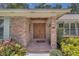 Close-up of the brick entryway with a wooden double door and lush surrounding greenery at 202 Riverview Dr, Longwood, FL 32779