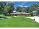 Classic brick home with a circular driveway surrounded by lush greenery and mature shade trees at 202 Riverview Dr, Longwood, FL 32779