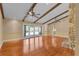Large living room boasts a beamed ceiling, hardwood floors, and a stone fireplace at 202 Riverview Dr, Longwood, FL 32779