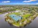 Aerial view of tennis courts surrounded by trees and a lake at 2274 Foliage Oak Ter, Oviedo, FL 32766
