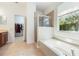 Bright bathroom with a soaking tub, glass-enclosed shower, and a view to the walk in closet at 2782 Cedar Knoll Dr, Apopka, FL 32712