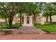 A lovely cream-colored home featuring an expansive brick driveway, manicured lawn, and mature trees at 3426 Cocard Ct, Windermere, FL 34786