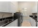 Bright laundry room with white cabinets, granite counters, stainless sink, and front loading machines at 3426 Cocard Ct, Windermere, FL 34786