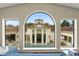Stunning view of the pool and backyard through an arched window from the interior at 3426 Cocard Ct, Windermere, FL 34786