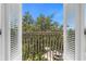 View from the balcony, showcasing lush green trees and a neighborhood street below, framed by white shutters at 3508 Porta Romano Way, Lake Mary, FL 32746