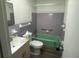 A bathroom featuring gray and green tile, a toilet, and a sink at 4204 Columbia St, Orlando, FL 32811