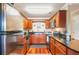 Cherry wood cabinets and stainless steel appliances compliment this kitchen with granite counters and wood floors at 4890 Conway Rd # 66, Orlando, FL 32812
