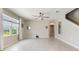 Neutral living room features tile floors, ceiling fan, large window, and access to bathroom at 6808 Cranes Roost Rd, Harmony, FL 34773
