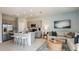 Modern living room and kitchen featuring an island with seating and stainless appliances at 7807 Waterscape Dr, Groveland, FL 34736