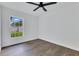 Bright bedroom features hardwood floors, a ceiling fan, and a large window allowing ample natural light at 8111 Lianna Dr, Orlando, FL 32822