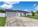 Single-story home with gray garage door, white painted brick and landscaped yard at 8111 Lianna Dr, Orlando, FL 32822