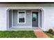 Inviting front porch with gray door, tiled floor and brick trimmed flower bed at 8111 Lianna Dr, Orlando, FL 32822