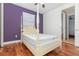 Bright bedroom featuring a four-poster bed, hardwood floors, and a purple accent wall at 8162 Prestbury Dr, Orlando, FL 32832
