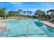 A serene community pool area surrounded by lush landscaping, lounge chairs, and clear blue water for relaxation at 8955 Fluffy Lie Ct, Davenport, FL 33896