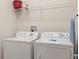 Bright laundry area includes a washer, dryer, shelving and ironing board at 9023 Shadow Mountain St, Davenport, FL 33896
