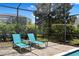 Backyard screened lanai area with two lounge chairs, privacy landscaping, and brick paver pool deck at 9023 Shadow Mountain St, Davenport, FL 33896