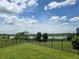 Expansive backyard view showcasing a lush green lawn and a serene lake, framed by a black iron fence at 9128 Sonoma Coast Dr, Winter Garden, FL 34787