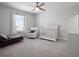 A Bedroom with a polka dot accent wall, crib, couch, and large window for natural light at 9128 Sonoma Coast Dr, Winter Garden, FL 34787