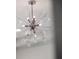 Close up of modern, starburst-style chandelier with unique glass and metal accents at 9128 Sonoma Coast Dr, Winter Garden, FL 34787
