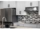 Close-up of a modern kitchen with sleek stainless steel appliances, stylish countertops, and a chic tile backsplash at 9128 Sonoma Coast Dr, Winter Garden, FL 34787