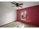 A bedroom with a ceiling fan, window, and red accent wall at 979 Mayfair St, Eustis, FL 32726